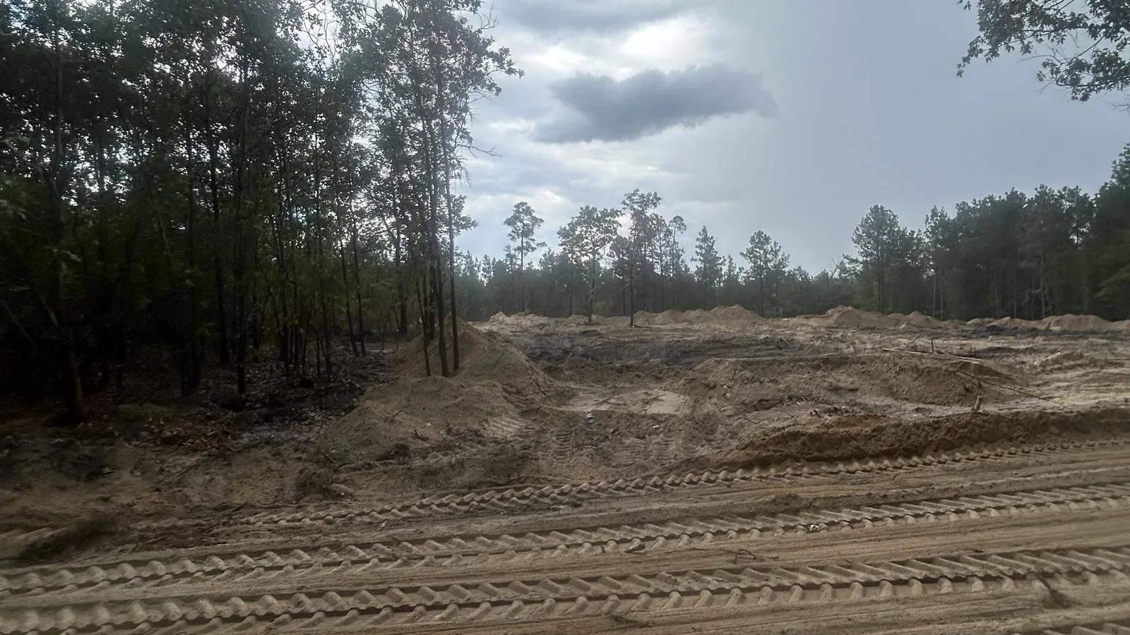 Cleared lot with sand piles along the woods, septic system installation