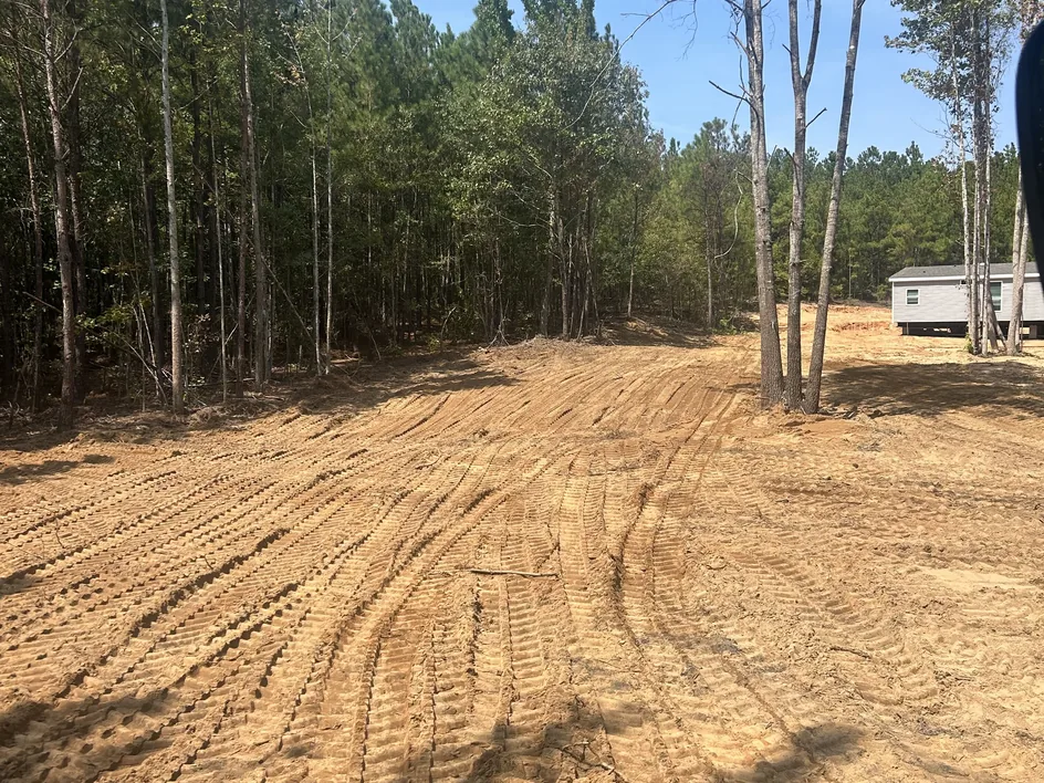 Cleared lot with fresh track marks and a manufactured home at the edge of the pines, mobile home septic systems