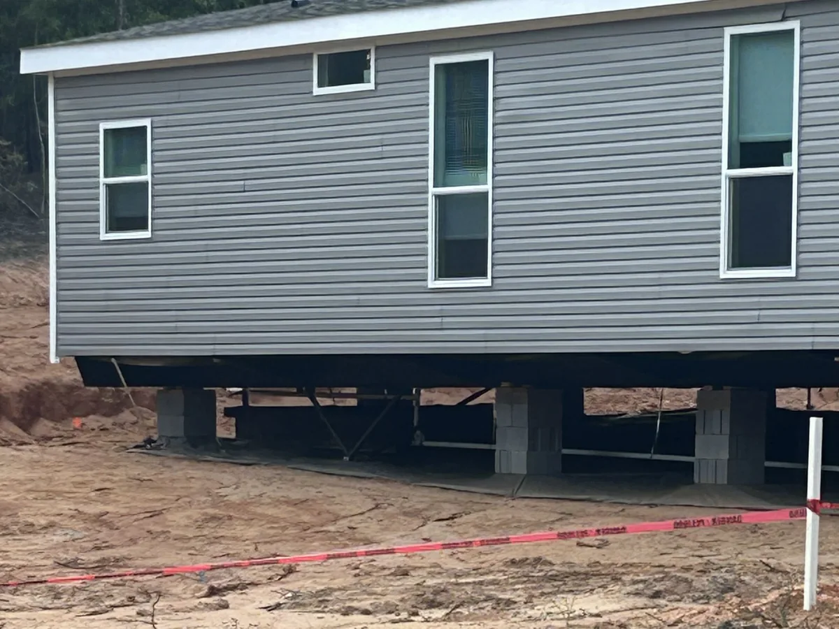 Manufactured home on block piers with red tape strung from a stake across the lot, mobile home septic systems