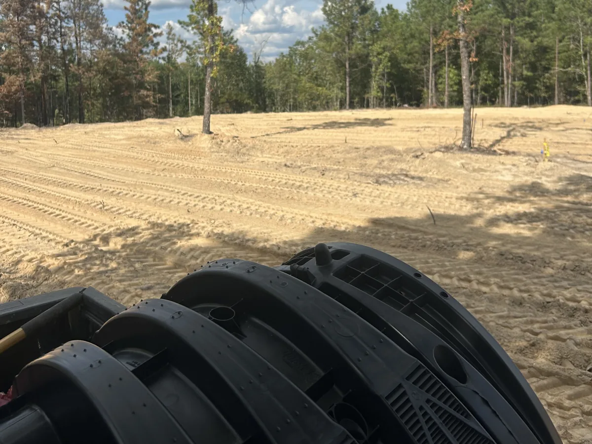 Drain field chambers loaded on a truck beside a cleared lot, septic system repair
