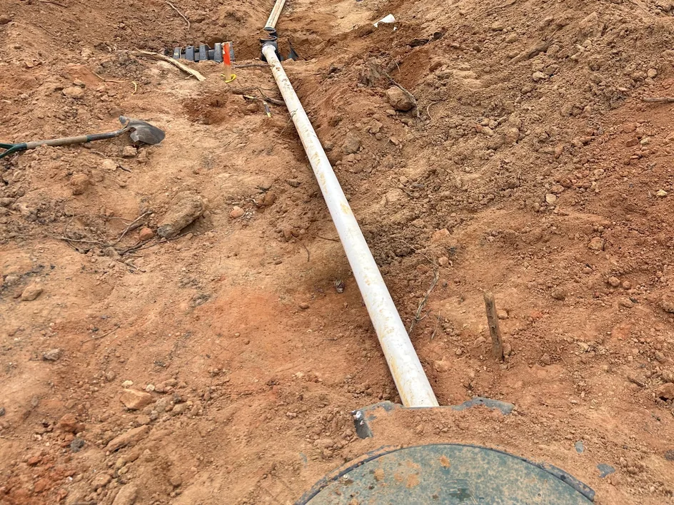 PVC outlet line running from the septic tank lid toward the drain field, septic system replacement