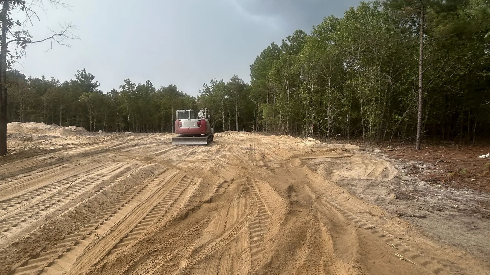 Excavator on a freshly cleared lot with track marks, septic system installation